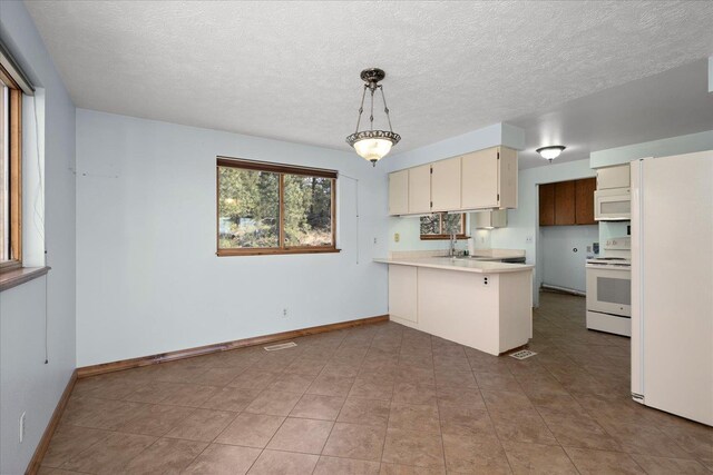 kitchen featuring a peninsula, white appliances, baseboards, light countertops, and a sink