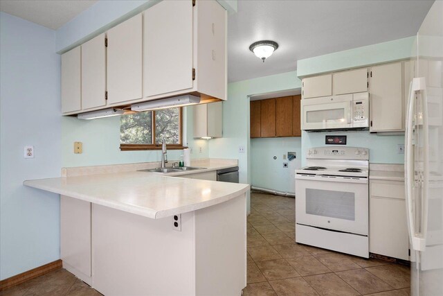kitchen featuring a sink, a peninsula, white appliances, and light countertops