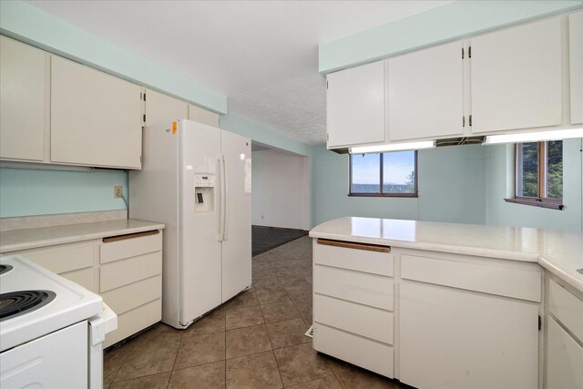 kitchen with light countertops, tile patterned flooring, white appliances, and white cabinetry