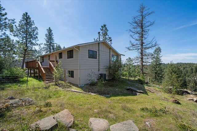 view of side of property with stairs, board and batten siding, central AC, and a deck