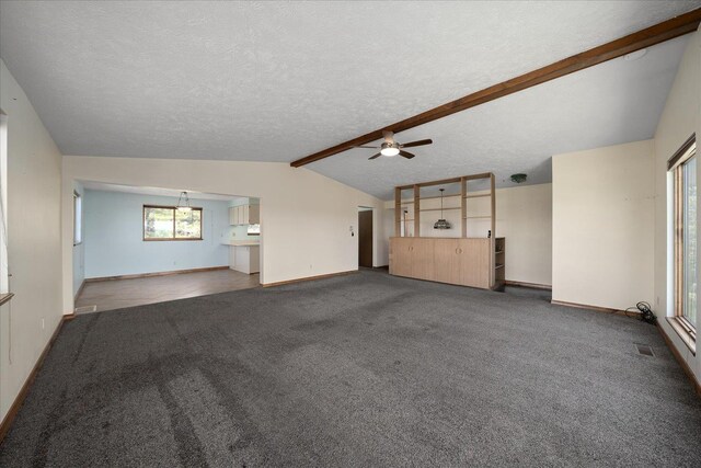 unfurnished living room featuring baseboards, a ceiling fan, lofted ceiling with beams, and carpet flooring