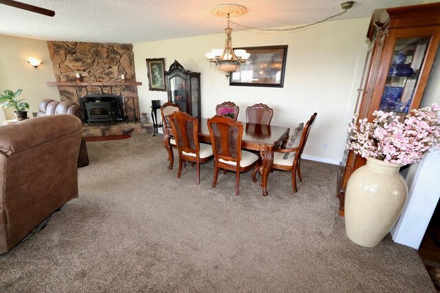 carpeted dining room with an inviting chandelier, a wood stove, and a textured ceiling