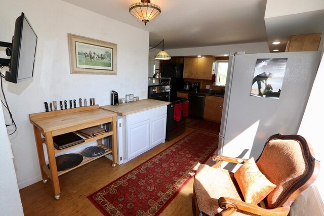 kitchen with electric stove, dishwashing machine, white cabinets, and light wood-style flooring