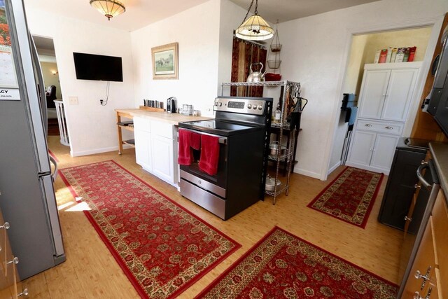 kitchen featuring baseboards, white cabinets, stainless steel appliances, and light wood-type flooring