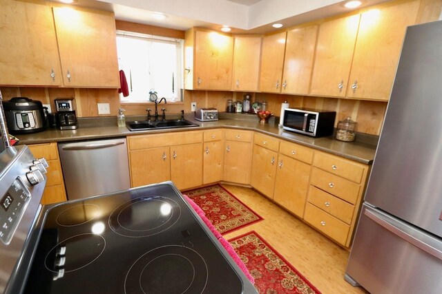 kitchen with stainless steel appliances, recessed lighting, a sink, and light wood finished floors
