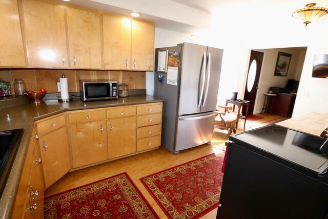 kitchen with decorative backsplash, dark countertops, a sink, light floors, and stainless steel appliances