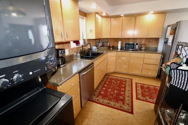 kitchen featuring light brown cabinets, recessed lighting, a sink, appliances with stainless steel finishes, and stacked washer / drying machine