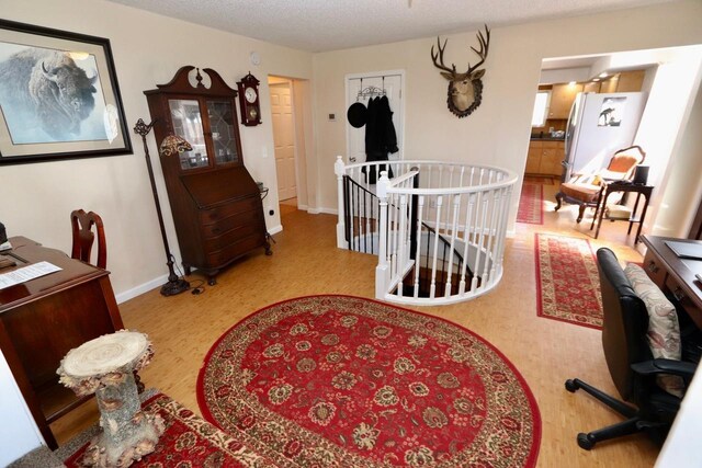 hall featuring baseboards, wood finished floors, and an upstairs landing