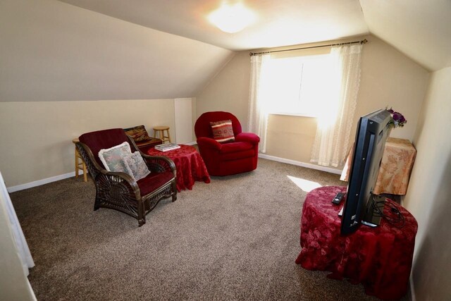 living area featuring carpet floors, baseboards, and vaulted ceiling