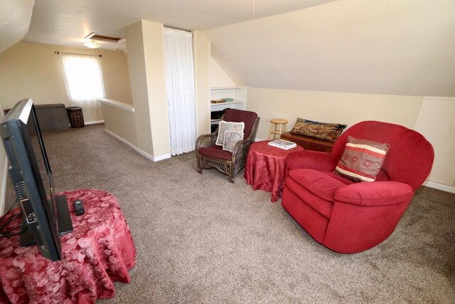 sitting room featuring carpet flooring, baseboards, vaulted ceiling, and visible vents