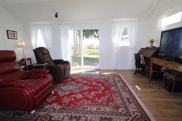 living room featuring plenty of natural light, lofted ceiling, and wood finished floors