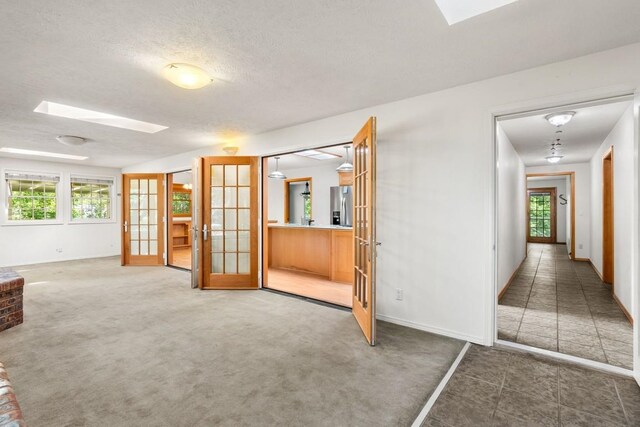 interior space with a skylight, plenty of natural light, and french doors
