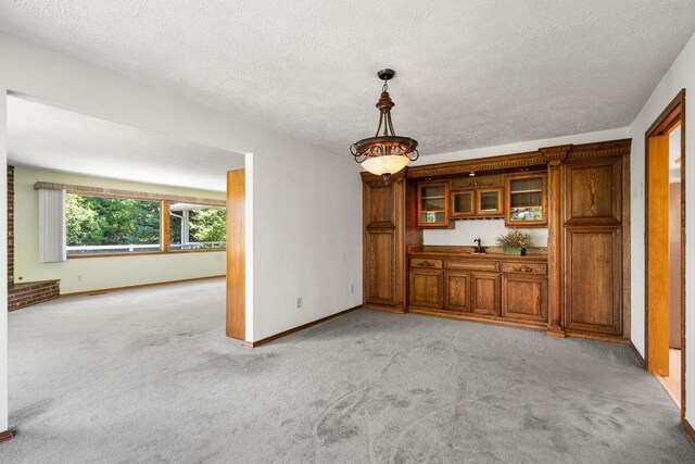 interior space with baseboards, a textured ceiling, and light colored carpet