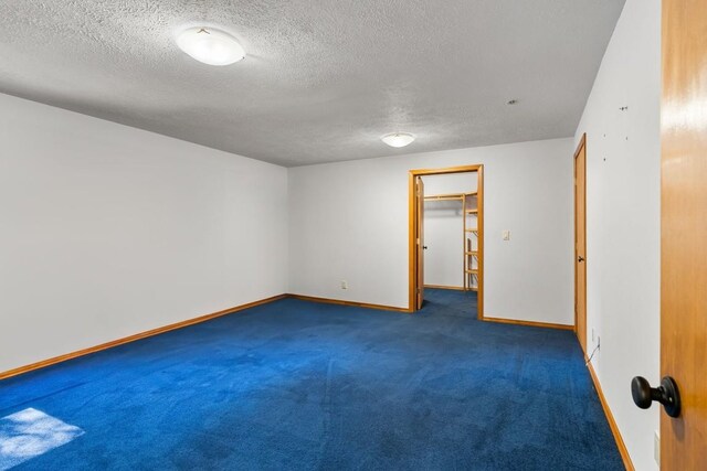 unfurnished room with baseboards, a textured ceiling, and carpet