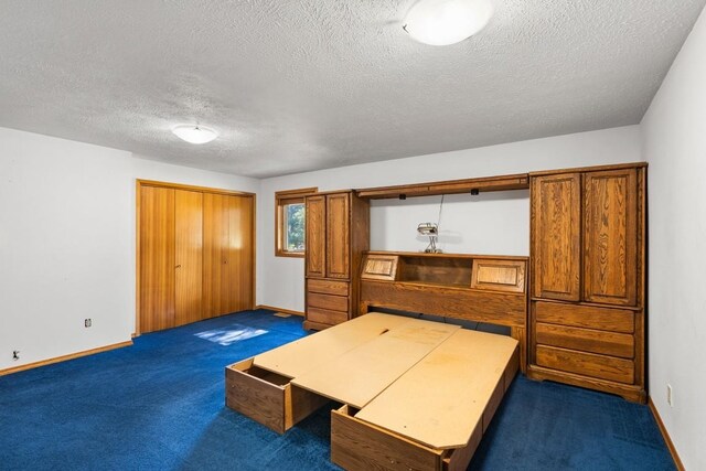 unfurnished bedroom featuring baseboards, dark carpet, and a textured ceiling