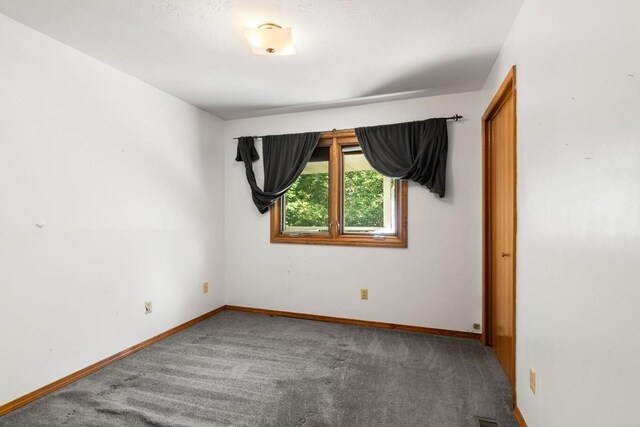 empty room featuring baseboards and carpet