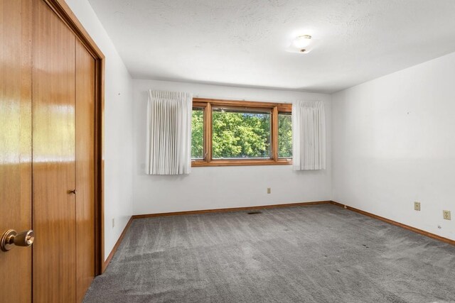 unfurnished bedroom with baseboards, visible vents, carpet, and a closet