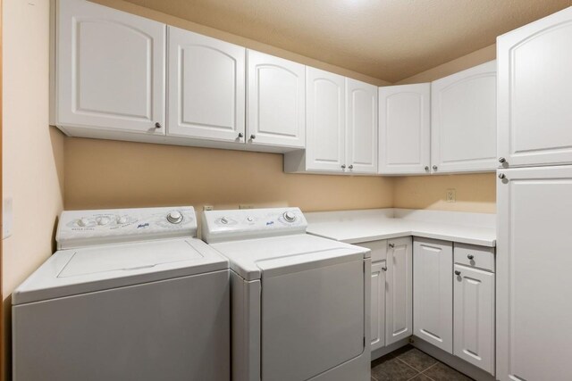 clothes washing area with cabinet space, washer and dryer, and dark tile patterned flooring