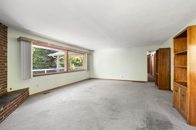 unfurnished living room with carpet flooring and baseboards
