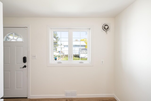 entryway featuring a healthy amount of sunlight, baseboards, wood finished floors, and visible vents
