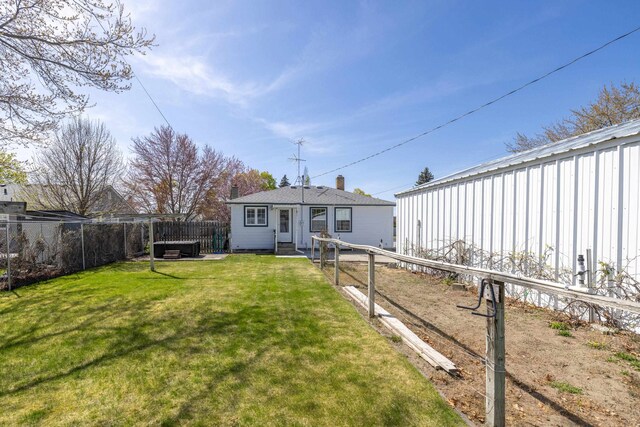 back of house featuring a lawn, a hot tub, and fence