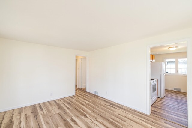 empty room featuring light wood-style floors, baseboards, and visible vents