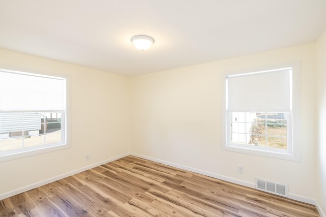 empty room with baseboards, light wood finished floors, and visible vents