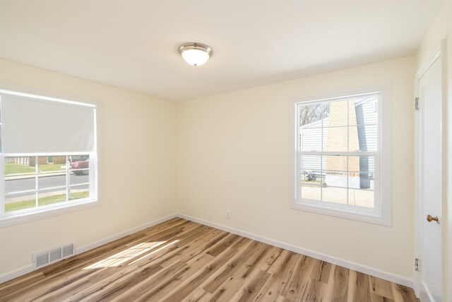 spare room featuring baseboards, visible vents, and light wood-style flooring