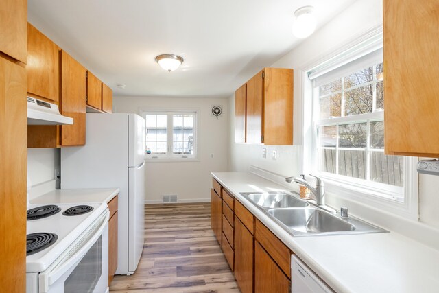 kitchen featuring white electric stove, visible vents, a sink, light wood finished floors, and under cabinet range hood