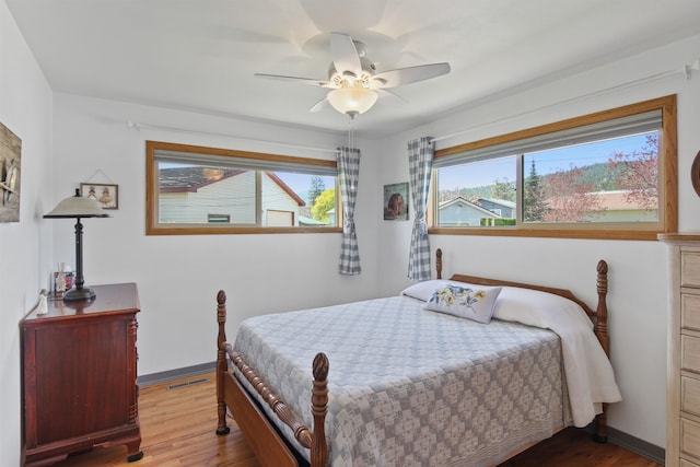 bedroom with a ceiling fan, baseboards, and wood finished floors