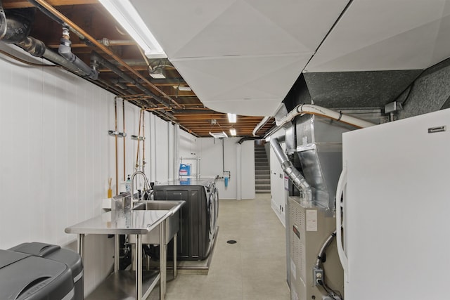 unfinished basement featuring freestanding refrigerator, a sink, and washer and clothes dryer