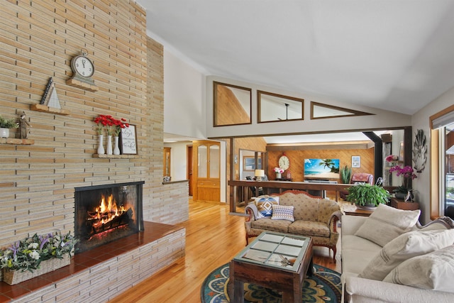 living area featuring high vaulted ceiling, wood walls, wood finished floors, and a fireplace