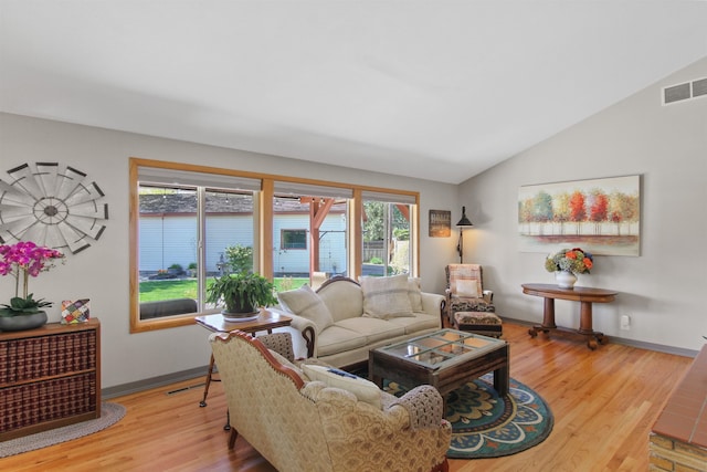 living area featuring wood finished floors, baseboards, lofted ceiling, and visible vents