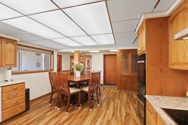 dining room with baseboards, light wood-type flooring, and a paneled ceiling