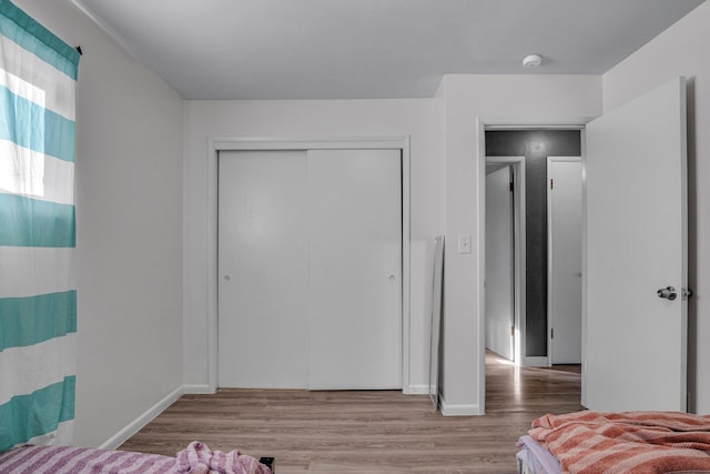 bedroom with baseboards, a closet, and wood finished floors