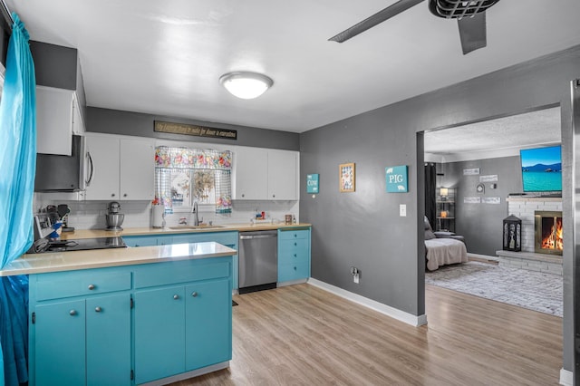 kitchen with light countertops, tasteful backsplash, a sink, light wood finished floors, and stainless steel appliances