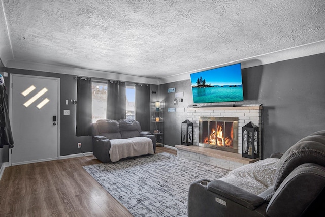 living room with baseboards, a textured ceiling, wood finished floors, and a fireplace
