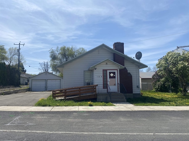 bungalow-style house with an outbuilding, a chimney, and a garage