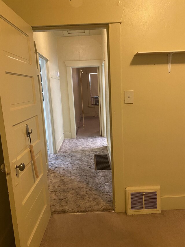 hallway featuring carpet floors, attic access, and visible vents