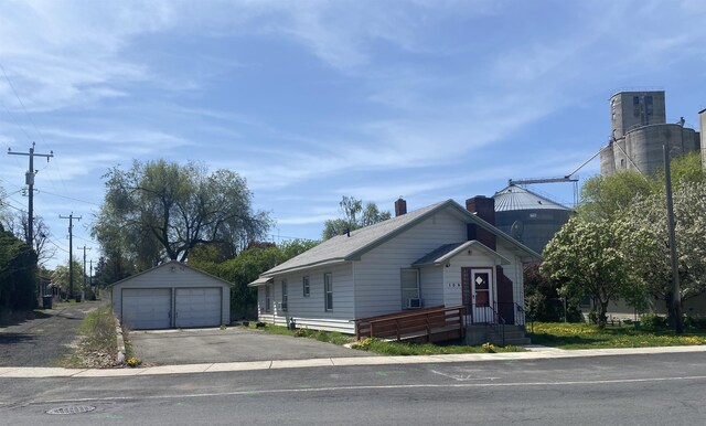 bungalow-style home featuring a detached garage, a chimney, and an outdoor structure