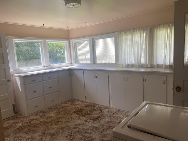 kitchen with washer / clothes dryer, white cabinets, and plenty of natural light