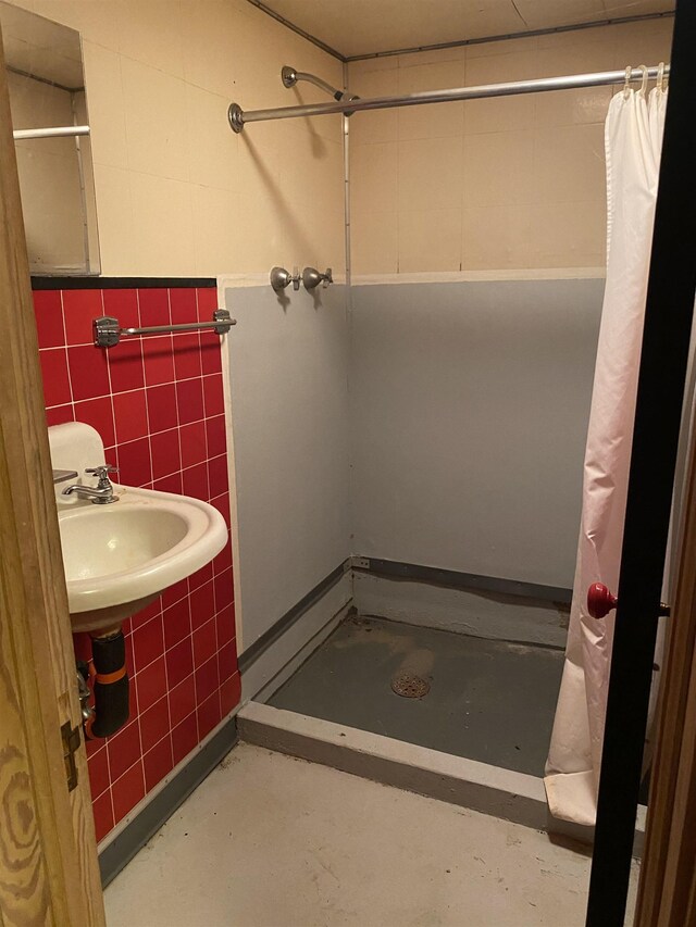bathroom with tile walls, concrete floors, a sink, and a stall shower