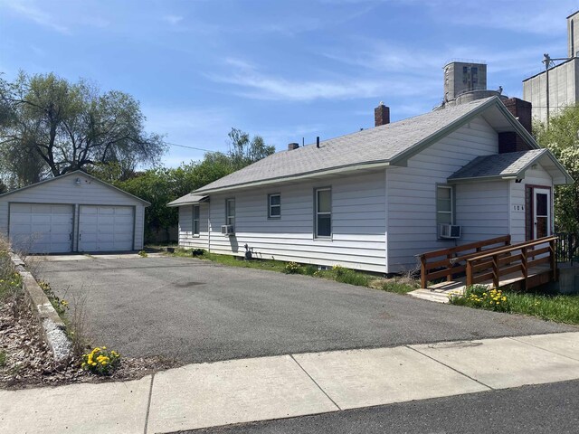 view of side of home featuring a detached garage, an outbuilding, a shingled roof, and a chimney