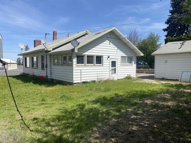 back of property featuring a chimney and a yard