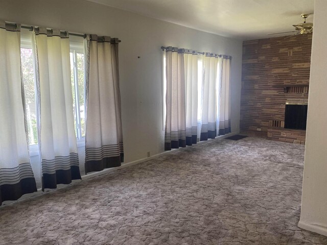 unfurnished living room with a ceiling fan, a wealth of natural light, and carpet