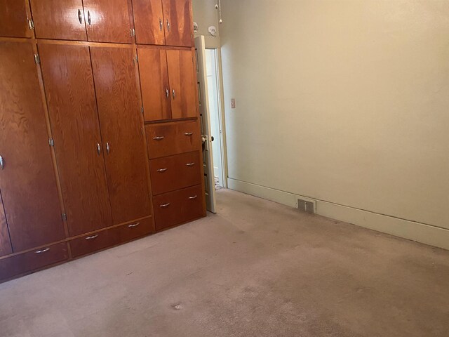 unfurnished bedroom with light colored carpet, baseboards, visible vents, and a closet