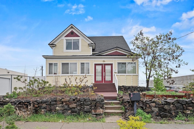 view of front facade featuring french doors, fence, a shingled roof, and entry steps
