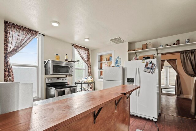 kitchen featuring appliances with stainless steel finishes, plenty of natural light, dark wood-style flooring, and visible vents