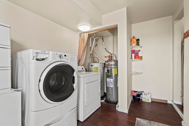clothes washing area featuring washing machine and clothes dryer, dark wood finished floors, laundry area, and electric water heater