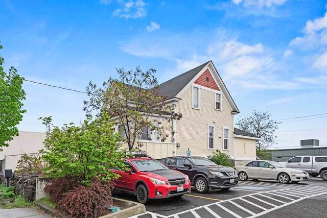 view of home's exterior featuring uncovered parking and roof with shingles